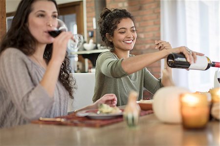 red wine pour - Two young women friends drinking red wine with meal at kitchen table Stock Photo - Premium Royalty-Free, Code: 614-08884484