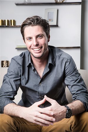 empresario (hombre) - Portrait of young man sitting on sofa, smiling Foto de stock - Sin royalties Premium, Código: 614-08884720