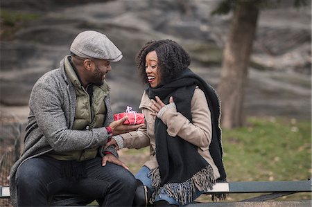 flat cap and scarf men - Romantic man handing girlfriend a gift in park Stock Photo - Premium Royalty-Free, Code: 614-08884736