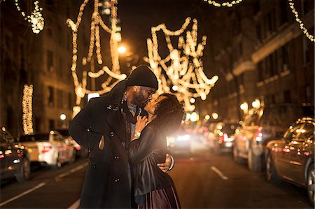 Romantic couple kissing by Christmas lights at night, New York, USA Fotografie stock - Premium Royalty-Free, Codice: 614-08884752