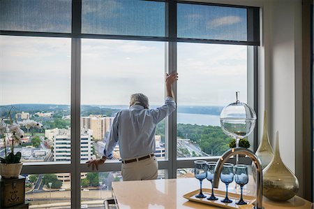 Senior man looking out of window of tall building, rear view Stock Photo - Premium Royalty-Free, Code: 614-08884903