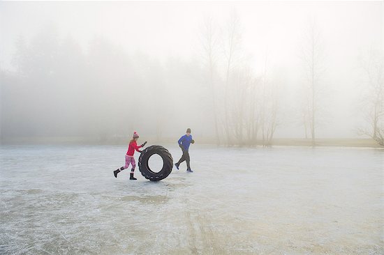 Woman rolling tyre on frozen lake Foto de stock - Sin royalties Premium, Código de la imagen: 614-08884960