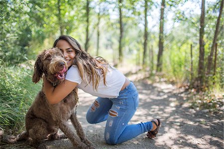 Portrait of teenage girl hugging cute dog on woodland path Stock Photo - Premium Royalty-Free, Code: 614-08884994
