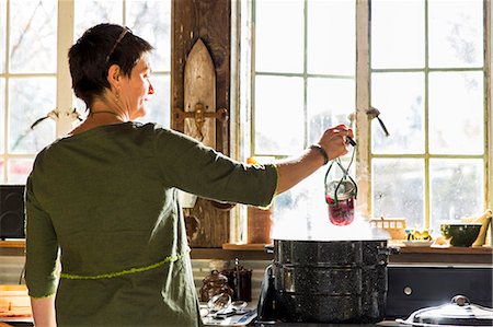 Rear view of woman removing beetroot preserves jar from steaming saucepan Foto de stock - Sin royalties Premium, Código: 614-08885002