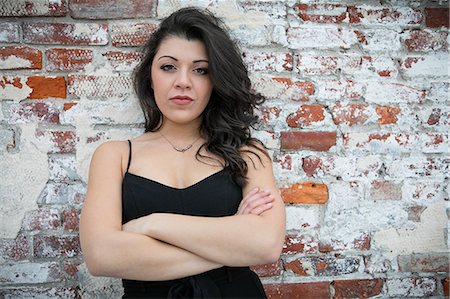 simsearch:614-08926220,k - Portrait of confident young woman with arms folded leaning against brick wall Stock Photo - Premium Royalty-Free, Code: 614-08885023