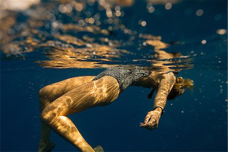 Underwater view of woman floating, Oahu, Hawaii, USA Stock Photo - Premium Royalty-Free, Code: 614-08880831