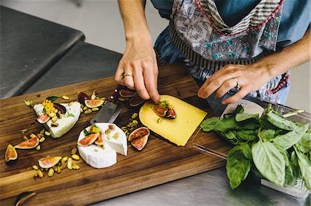 simsearch:6126-08635695,k - Woman preparing variety cheese plate with figs, nuts, pistachios, basil on wooden chopping board Foto de stock - Sin royalties Premium, Código: 614-08880895