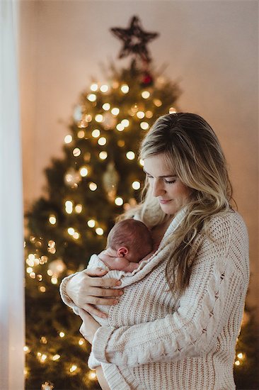 Mid adult woman cradling new born baby daughter wrapped in cardigan at Christmas Stock Photo - Premium Royalty-Free, Image code: 614-08880950