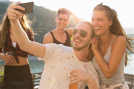 selfie drinking - Young man taking selfie with female friend at waterfront roof terrace party, Budapest, Hungary Stock Photo - Premium Royalty-Free, Code: 614-08880989