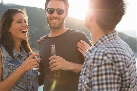 simsearch:614-08880988,k - Three adult friends laughing and partying on roof terrace Photographie de stock - Premium Libres de Droits, Code: 614-08880998