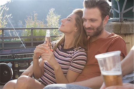 simsearch:614-08880988,k - Young woman relaxing on boyfriends lap at roof terrace party Photographie de stock - Premium Libres de Droits, Code: 614-08881033