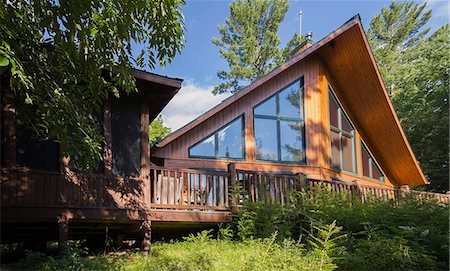 Back view of a milled cottage style flat log profile home with elevated wooden deck and landscaping in summer, Mt-Tremblant, Quebec, Canada Photographie de stock - Premium Libres de Droits, Code: 614-08881117