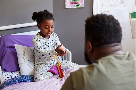 Father talking to young girl on bed with trophy Stock Photo - Premium Royalty-Free, Code: 614-08881217