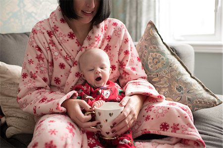 Mother and baby boy holding mug, sitting on sofa Stock Photo - Premium Royalty-Free, Code: 614-08881210