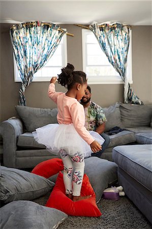 Girl in tutu dancing on cushions for father Stock Photo - Premium Royalty-Free, Code: 614-08881283