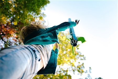 Low angle view of girl throwing toy rocket skyward from garden Stock Photo - Premium Royalty-Free, Code: 614-08881309