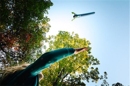 Low angle view of girl watching toy rocket flying toward blue sky Photographie de stock - Premium Libres de Droits, Code: 614-08881310