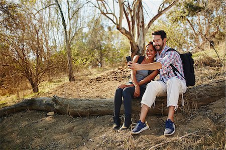 simsearch:649-09025419,k - Mid adult couple hiking, sitting on log taking smartphone selfie Stock Photo - Premium Royalty-Free, Code: 614-08881322