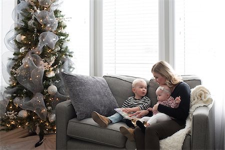 simsearch:614-06897571,k - Mother and children sitting on sofa, looking at book Foto de stock - Royalty Free Premium, Número: 614-08881363