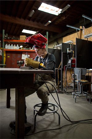 Female metalsmith preparing metal rods at workshop bench Stock Photo - Premium Royalty-Free, Code: 614-08881415