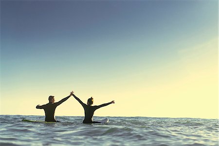 Surfing couple on surfboards holding hands in sea, Newport Beach, California, USA Stock Photo - Premium Royalty-Free, Code: 614-08881429