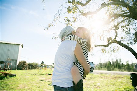 striped woman dress - Mid adult woman and daughter hugging in sunlit park Stock Photo - Premium Royalty-Free, Code: 614-08908281