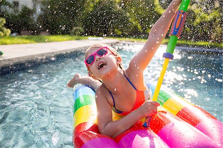 simsearch:695-05764298,k - Girl in bikini on inflatable playing with water gun in outdoor swimming pool Photographie de stock - Premium Libres de Droits, Code: 614-08908361