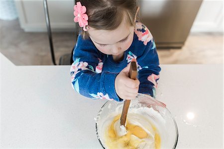 Overhead view of girl stirring mixing bowl at kitchen counter Stock Photo - Premium Royalty-Free, Code: 614-08908396