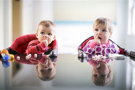 funny mischievous babies - Male and female toddlers at kitchen counter picking nose and eating sweets Stock Photo - Premium Royalty-Free, Code: 614-08908404