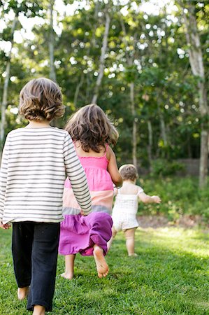Rear view of female toddler followed by boy and girl in garden Stock Photo - Premium Royalty-Free, Code: 614-08908425