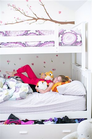 Portrait of girl lying on bunk bed with soft toys Fotografie stock - Premium Royalty-Free, Codice: 614-08908488