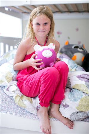Portrait of girl sitting on bunk bed holding piggy bank Fotografie stock - Premium Royalty-Free, Codice: 614-08908489