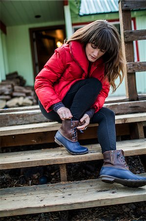 Young woman sitting on step, tying boot laces Foto de stock - Sin royalties Premium, Código: 614-08908571