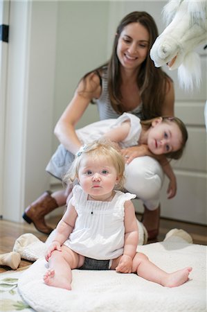 simsearch:614-06897884,k - Portrait of baby girl sitting on floor with mother and sister behind Foto de stock - Sin royalties Premium, Código: 614-08926082