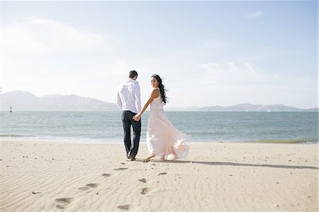 simsearch:614-07708168,k - Woman looking back while strolling hand in hand with boyfriend on beach Stock Photo - Premium Royalty-Free, Code: 614-08926110