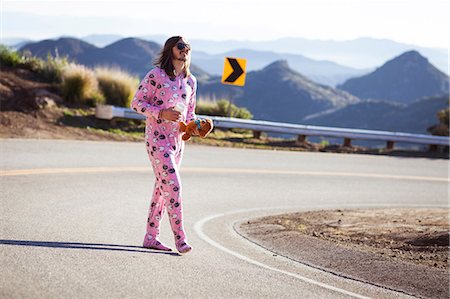 Man wearing pink onesie walking in road carrying teddybear, Malibu Canyon, California, USA Stock Photo - Premium Royalty-Free, Code: 614-08926288