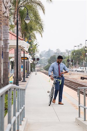 simsearch:614-08926442,k - Young businessman cyclist looking at watch on railway station platform Stock Photo - Premium Royalty-Free, Code: 614-08926454