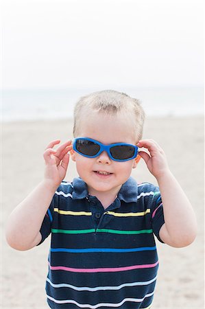 Portrait of male toddler putting on blue sunglasses at beach Photographie de stock - Premium Libres de Droits, Code: 614-08946119
