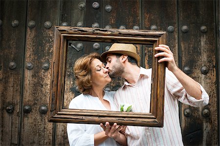 family portraits in frames - Portrait of adult son kissing mother on cheek, holding wooden frame in front of their faces, Mexico City, Mexico Stock Photo - Premium Royalty-Free, Code: 614-08946180