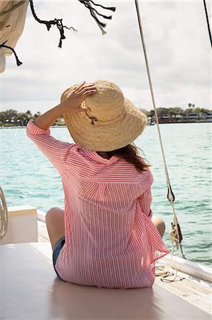 simsearch:614-06442936,k - Mid adult woman sitting on deck of sailing boat, holding onto hat, rear view Photographie de stock - Premium Libres de Droits, Code: 614-08946266