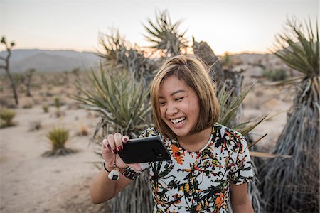 Young woman taking smartphone selfie in Joshua Tree National Park at dusk, California, USA Stock Photo - Premium Royalty-Free, Code: 614-08946320