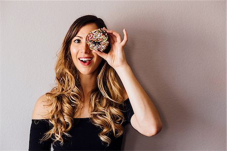 donut hole - Portrait of young woman with long blond hair holding doughnut hole over eye Stock Photo - Premium Royalty-Free, Code: 614-08946388