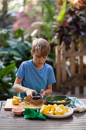 Boy preparing lemons for lemonade at garden table Stock Photo - Premium Royalty-Free, Code: 614-08946608