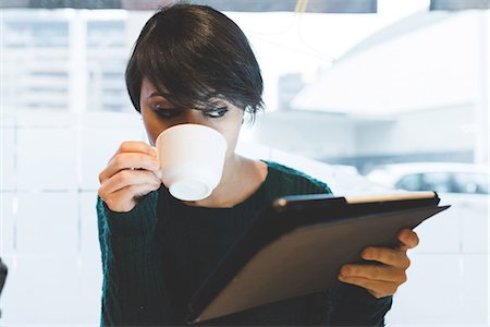 Woman in cafe looking at digital tablet and drinking coffee Photographie de stock - Premium Libres de Droits, Code: 614-08946732