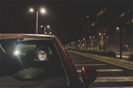 Woman looking out of car windscreen on city roadside at night Stock Photo - Premium Royalty-Free, Image code: 614-08946828