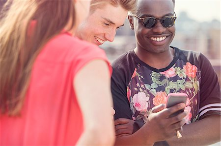 simsearch:649-08328059,k - Three young adult friends looking at smartphone at roof party in London, UK Fotografie stock - Premium Royalty-Free, Codice: 614-08984041