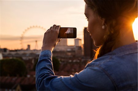 Young woman photographing skyline at sunset roof party in London, UK Stock Photo - Premium Royalty-Free, Code: 614-08984054