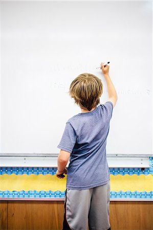 Young boy writing on whiteboard, rear view Stock Photo - Premium Royalty-Free, Code: 614-08984138