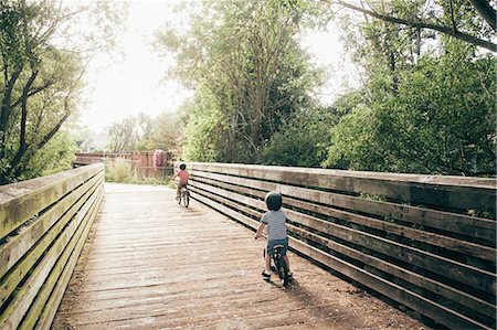 simsearch:6126-09267379,k - Two young boys riding bicycles across bridge, rear view Photographie de stock - Premium Libres de Droits, Code: 614-08984133