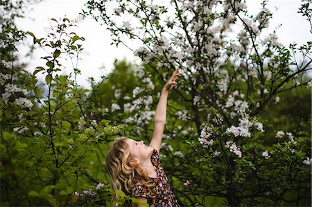 simsearch:649-09258032,k - Girl with wavy blond hair reaching up to tree blossom Fotografie stock - Premium Royalty-Free, Codice: 614-08984254